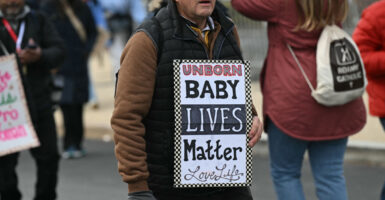 A man holds up a sign, "Unborn Babies Lives Matter: Love Life" at the March for Life.