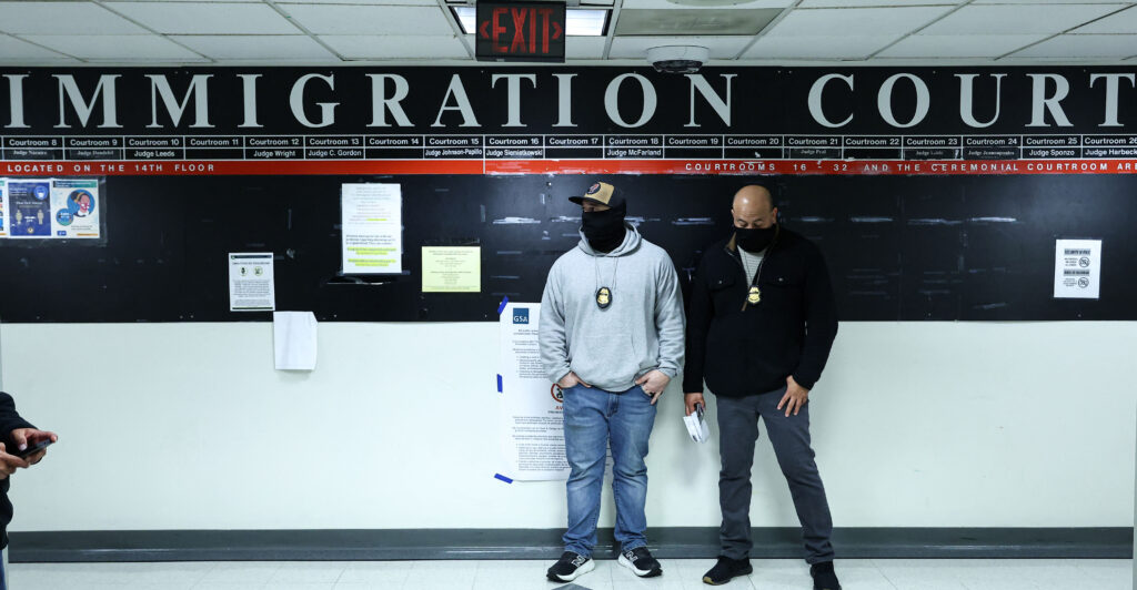 Masked federal agents stand in a hallway at the New York Federal Plaza Immigration Court inside the Jacob K. Javitz Federal Building in New York on March 5, 2026. US President Donald Trump has made deporting undocumented immigrants a key priority for his second term, after successfully campaigning against an alleged "invasion" by criminals. (Photo by CHARLY TRIBALLEAU / AFP via Getty Images)