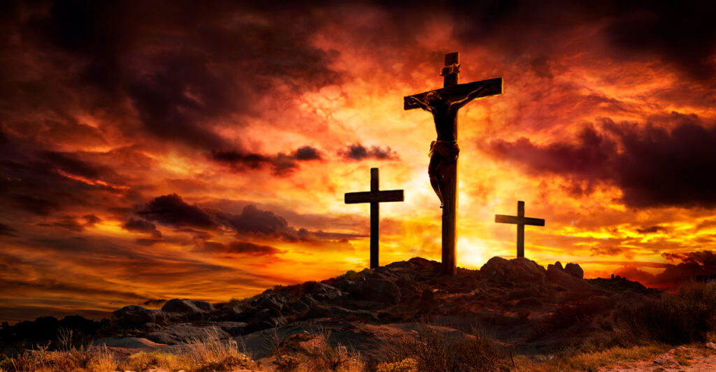 A graphic representation of Jesus on the Cross at Calvary, silhouetted against a cloudy orange sky.