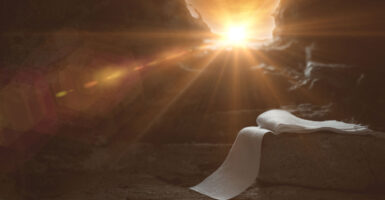 Artistic rendering of Jesus's empty tomb, with his burial shroud laying on stone and a burst of sunlight through the entrance.