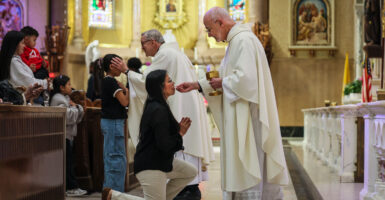 Boston, MA - April 23: Rev. James Wallace, C.Ss.R., distributes communion to a parishioner during afternoon Mass at the Basilica of Our Lady of Perpetual Help on April 23, 2025. The Redemptorists have ministered to this parish since its founding in 1870, serving a congregation that now includes immigrants from Ethiopia, Nigeria, and Haiti Wikipedia alongside longtime members. Despite Catholic identification in Boston falling from nearly one-third of adults in 2014 to 24% in 2023-2024, the basilica remains committed to nurturing a strong, open, and inclusive congregation that reflects the city's changing demographics. (Photo by Erin Clark/The Boston Globe via Getty Images)