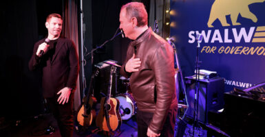 Eric Swalwell speaks to Adam Schiff on a small club stage in front of a "Swalwell for Governor" banner.