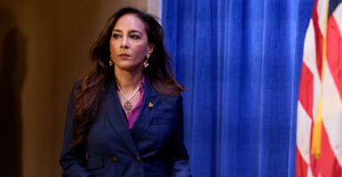 Assistant AG for Civil Rights Harmeet Dhillon in a blue jacket walks onto a stage.