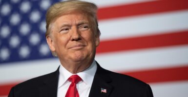 Donald Trump smiling in front of a U.S. flag