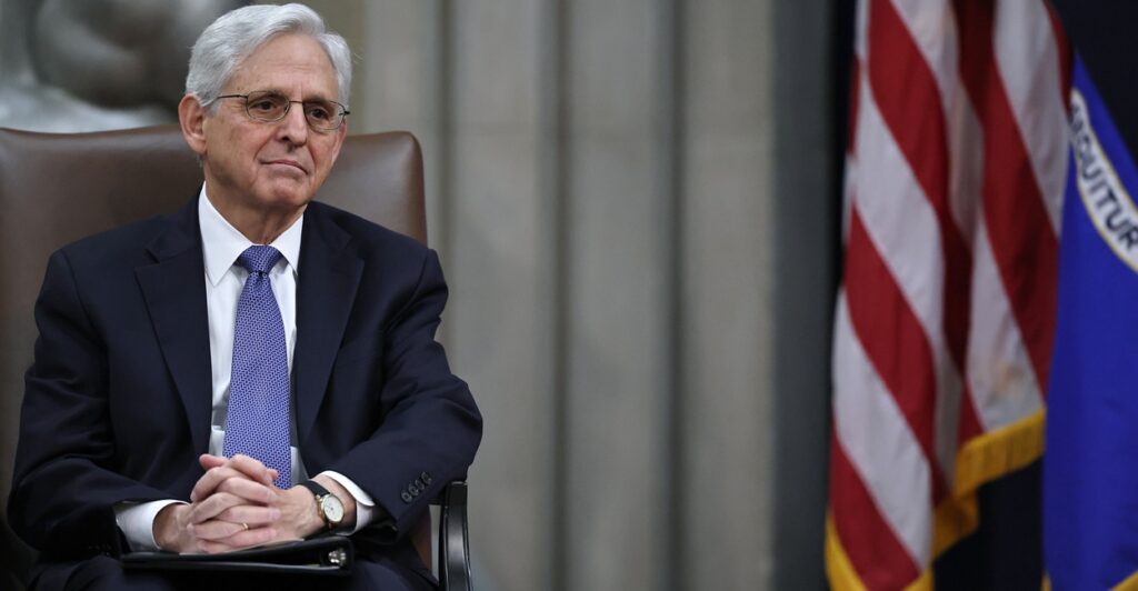 Merrick Garland seated by an American flag