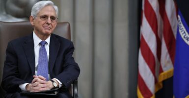 Merrick Garland seated by an American flag
