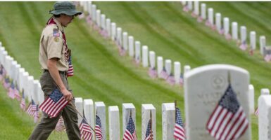 A scout placing flags by veterans' graves
