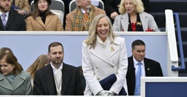 Abigail Spanberger standing and smiling in a white coat with other people seated nearby