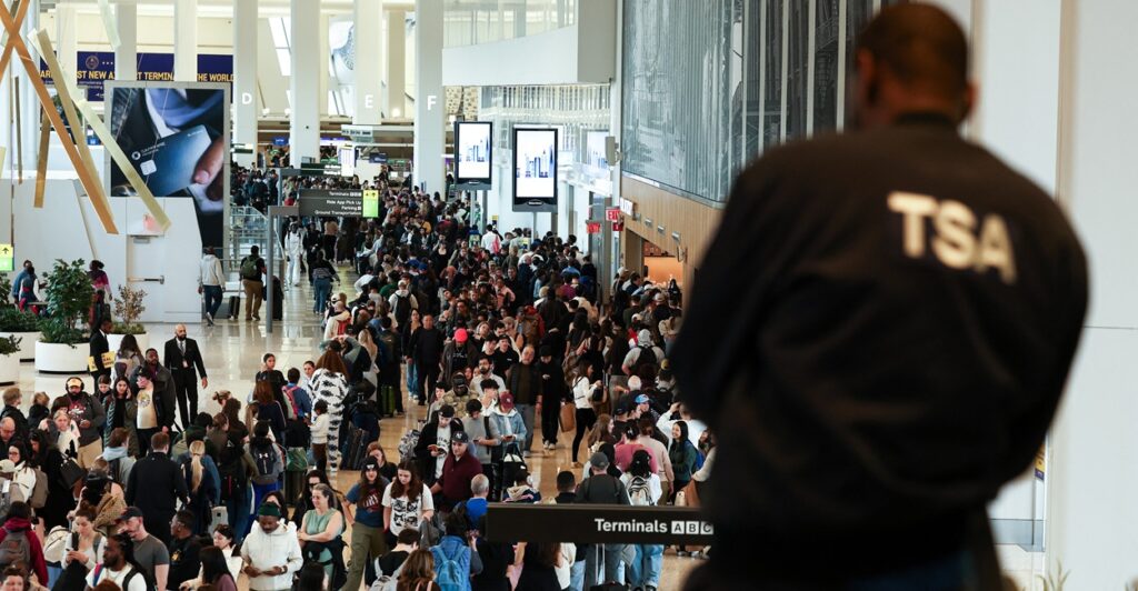 A TSA agent from the back looking at long lines in an airport