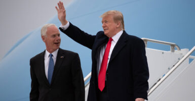 President Donald Trump waves while standing with Sen. Ron Johnson.
