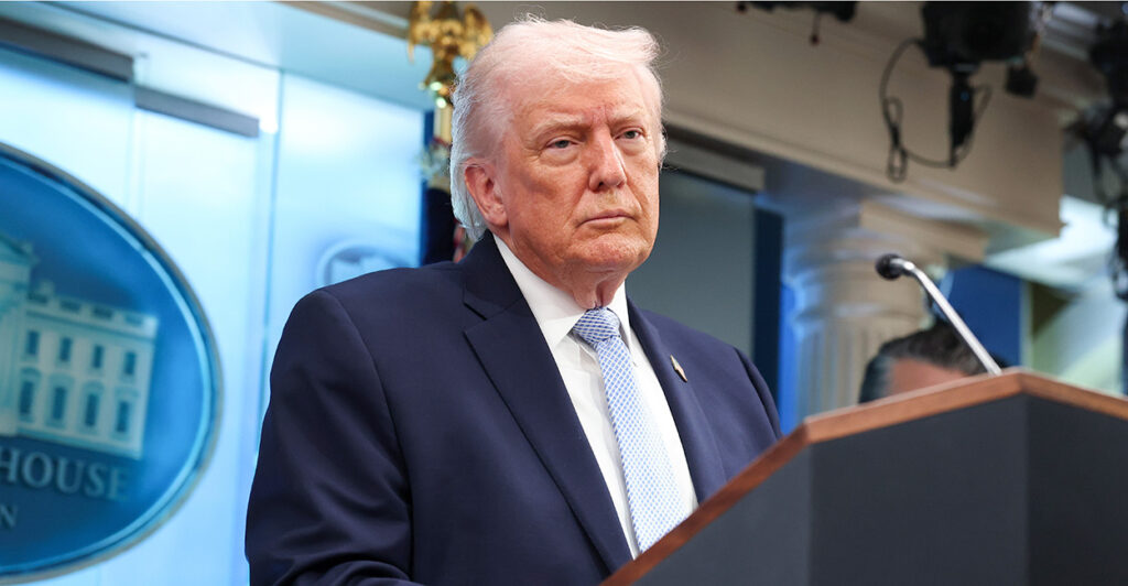 President Donald Trump stands behind a podium in the White House briefing room.